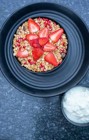 Breakfast granola with yogurt and strawberries on a black plate on a dark background. High quality photoの写真素材