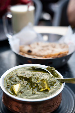 A bowl of Palak Paneer made of Paneer cheese dipped in mildly spiced Spinach gravy on wooden...