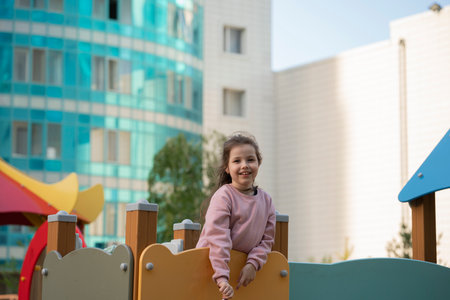 A seven-year-old girl in the yard on the playground.の写真素材