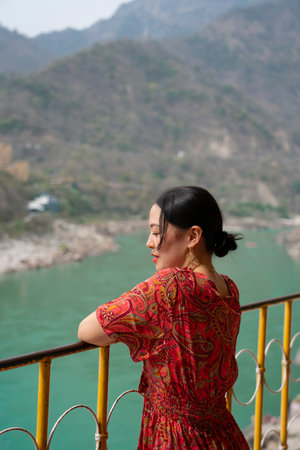 Young woman stands on a balcony, looking at a river. High quality photo
