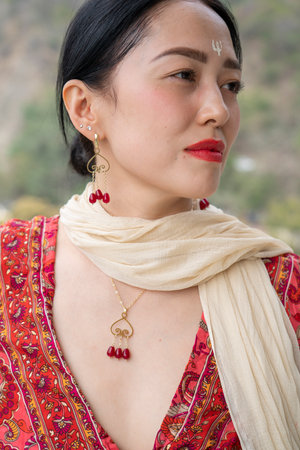 Gold jewelry with garnet on an Asian girl in a red dress. High quality photo