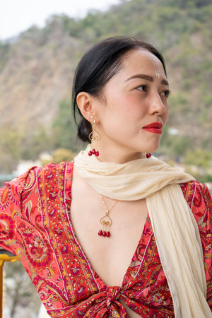 Gold jewelry with garnet on an Asian girl in a red dress. High quality photo