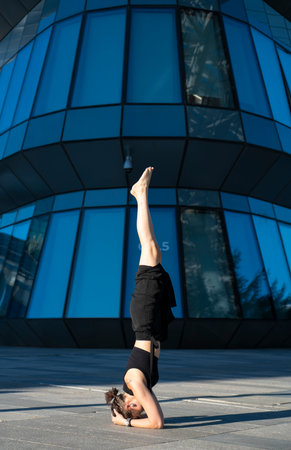 Young woman doing yoga headstand on street in front of building.の写真素材