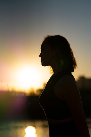 Summer portrait of young Asian woman in black clothes, backlight, golden hour.の写真素材