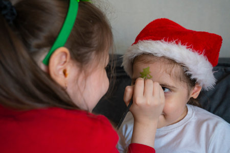 The older sister gives her younger sisters Christmas face painting.の写真素材