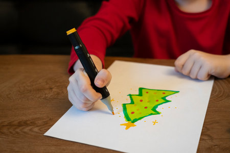 A girl draws a Christmas tree with a markerの写真素材