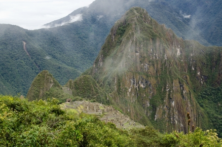 View from the Inca trail on the shoulder of the Machu Picchu Mountain towards the Inca ruins of Machu Picchu with the Huayna Picchu peak towering over the sceneの写真素材