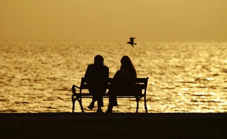 People sitting on a bench under sunsetの写真素材