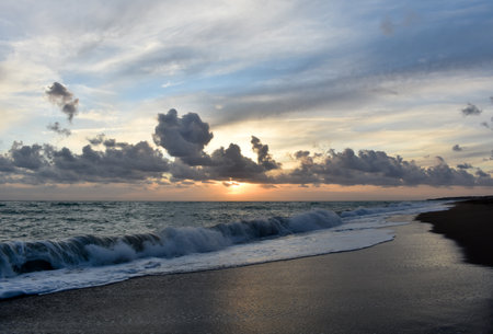 Beautiful sunset scene on a beach with sea, waves and cloudsの写真素材