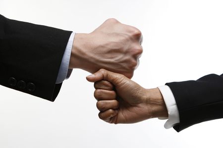 Two fists, one on top of the other. One belongs to a caucasian male the other belongs to an Indian womanの写真素材