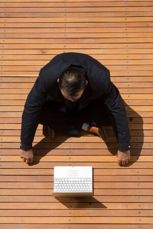 Latin american businessman sitting cross legged and working on his laptopの写真素材