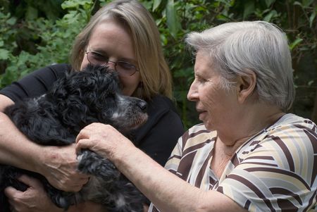 Woman with her elderly mother and a puppy relaxing in a gardenの写真素材