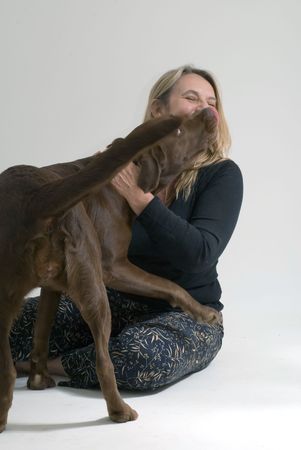 A shot of woman sitting playing with her dog, who's licking her face.の写真素材