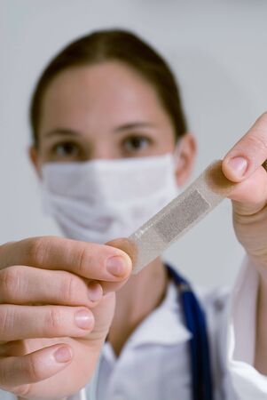 A of a nurse holding up an adhesive bandage in front of her face.の写真素材