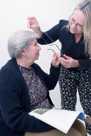 An isolated shot of a adult child putting glasses on her elderly mother.の写真素材