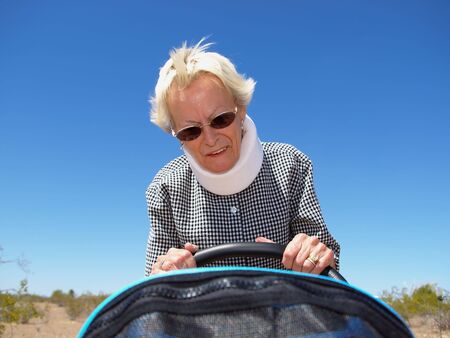 An isolated shot of a grandmother, wearing whiplash neck-brace, pushing a  stroller.の写真素材