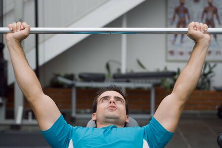 An isolated shot of male weightlifter bench pressing a barbell.