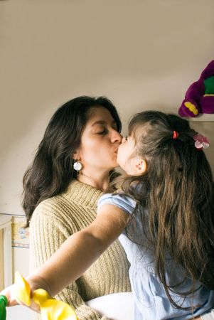 A mother kissing her daughter.