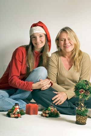 Two women sitting on the floor with Christmas decoration in front of them.の写真素材