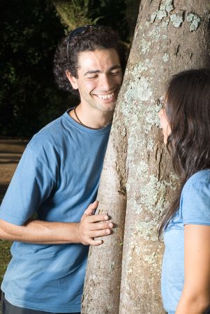 Couple leaning against at tree. He is smiling playfully. Vertically framed photographyの写真素材