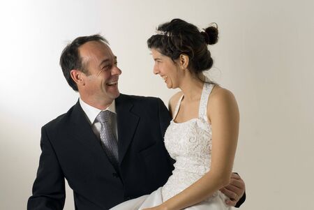 A newly married couple, smile at each other, wife sits on husbands lap. - horizontally framedの写真素材