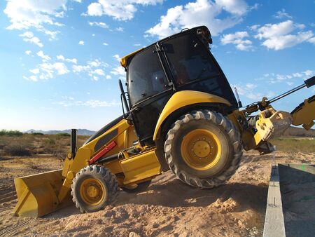 A large machine shovel is scooping dirt on an excavation site.  Horizontally framed shot.
