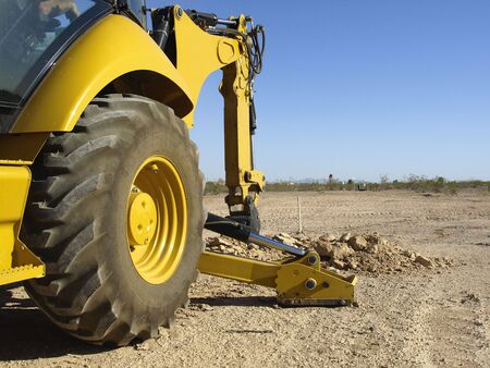 A giant steam shovel is digging into the dirt.  Horizontally framed shot.