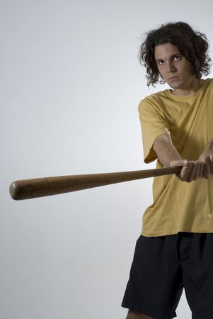 Man swings a baseball bat and wears an angry expression on his face. Vertically framed photograph
