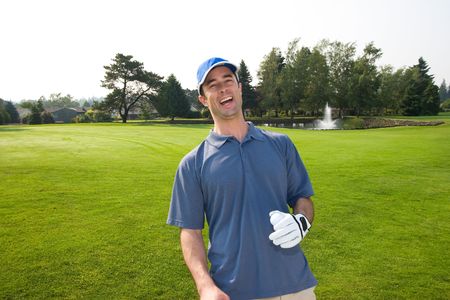 A man is standing on a golf course.  He is laughing and looking at the camera.  Horizontally framed shot.の写真素材