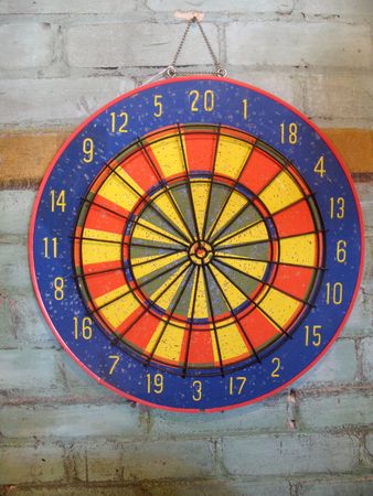 A colorful dartboard is displayed sideways on a brick wall.  Horizontally framed photo.の写真素材