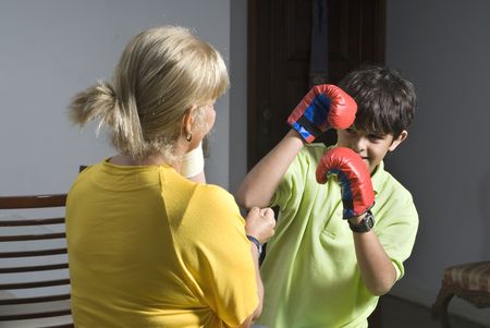 A woman and her son are playing and pretending to box each other.  He is wearing boxing gs.  They are smiling and looking at the camera.  Horizontally framed shot.の写真素材