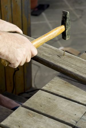 A man, hammering a nail into a piece of wood. Vertically framed shot.の写真素材