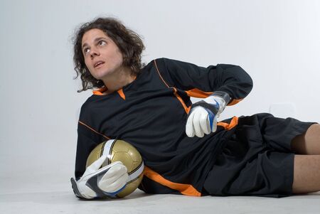 A man is dressed in a soccer uniform and posing in a studio.  He is holding a soccerball and looking away from the camera.  Horizontally framed shot.の写真素材