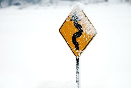Windy road sign with snow on it. Horizontally framed photo.の写真素材