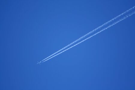 A jet stream in a blue sky. Horizontally framed shot.