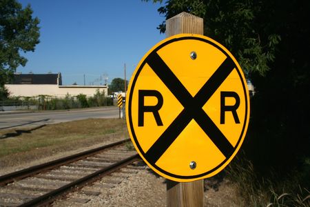 A railroad crossing sign and a railroad track behind it. Horizontally framed shot.の写真素材