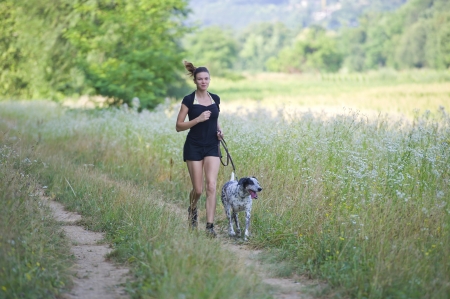 Dogs on leash runs between nature with its proprietaryの写真素材