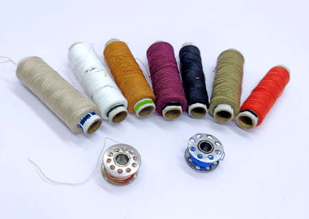 Old vintage hand sewing machine Colored thread coils or bobbin on white background, sewing machine...