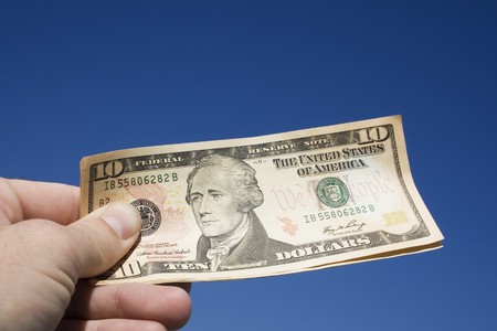 Ten dollar bills in a hand.   It could be a transaction, buying, handing over money or conversely a...