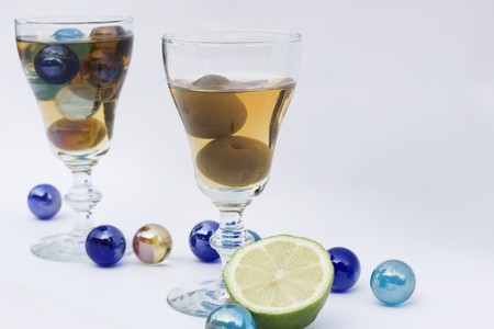 Two glasses of Japanese wine.  One has some plums in and the other marbles.  It's playful and shows the fun and relaxing side of wine.の写真素材