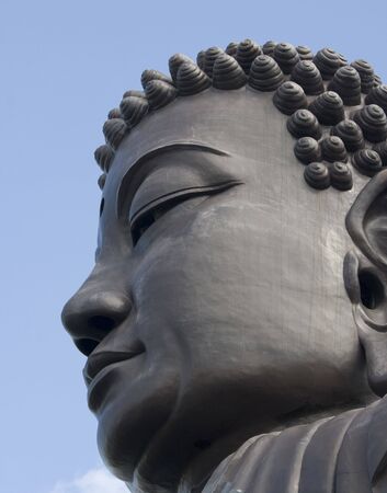 This is the head of a large buddha against a blue sky backdrop.  の写真素材
