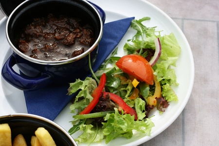 A stew with fresh salad and some fries.の写真素材