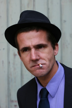 A man dressed in retro clothes, smoking a cigarette.  He looks moody and deep in thought.の写真素材