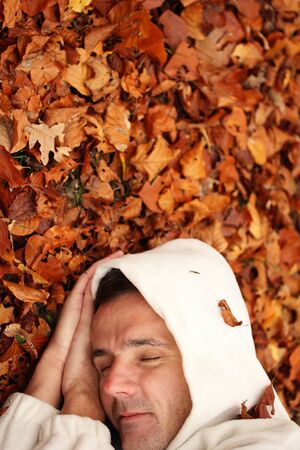 At peace with nature - man sleeping on some fallen leavesの写真素材