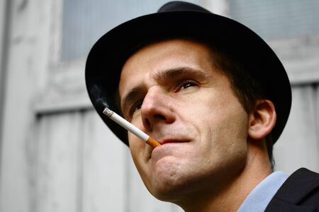 A man dressed in retro clothes, smoking a cigarette   He looks moody and deep in thought の写真素材