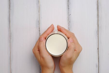 Milk in hand on white wood table background style and copy space, top view, selective focus.の写真素材