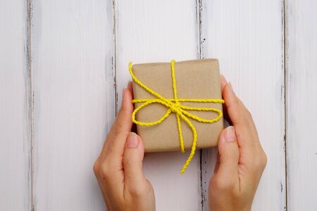 Gift box in hand for important day on white wood background, top view.の写真素材