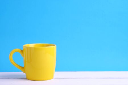 Close up of one yellow cup on white wood table and blue background concept, with blank space.の写真素材