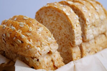 Whole grain bread isolated in basket on wooden background, close up and selective focus.