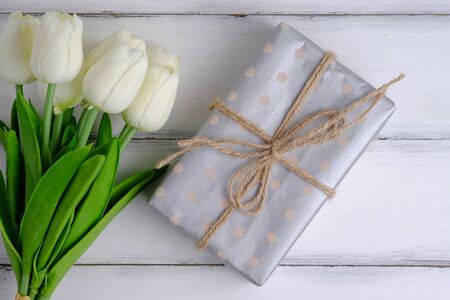 Beautiful gift box and tulips in important day on white wood  background vintange style, top view.